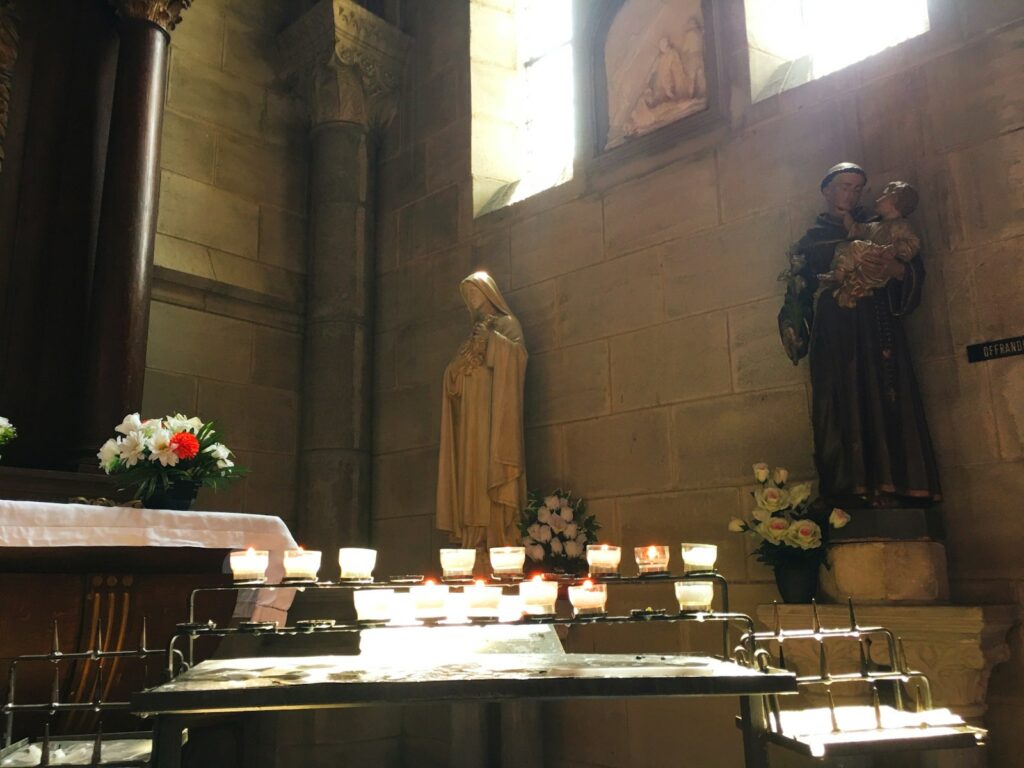 candles are lit in front of a statue in a church